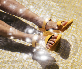 A model showcasing the yellow sandals while standing in water