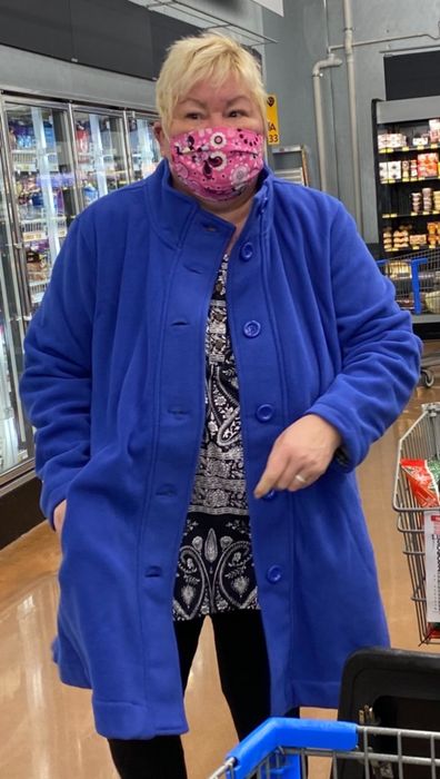 A reviewer wearing a blue coat layered over a black and white outfit