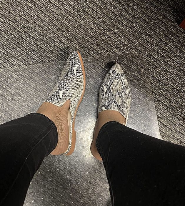 Feet showcasing a pair of snakeskin mules