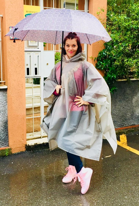 reviewer holding an umbrella while wearing pink high-top sneakers