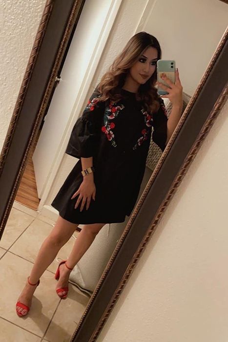 A reviewer showcasing the dress in black adorned with intricate floral embroidery