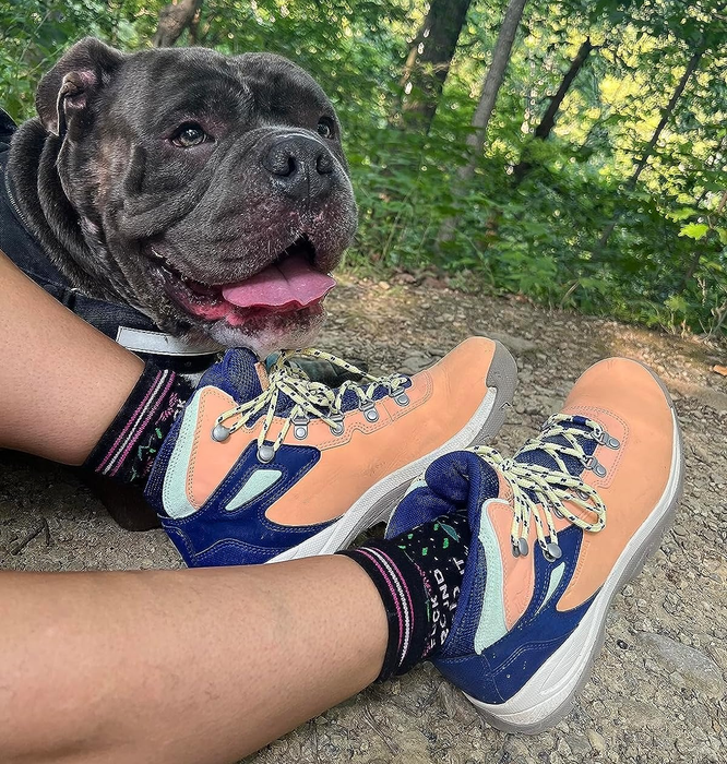 reviewer walking on a trail wearing the peach-colored hiking boots