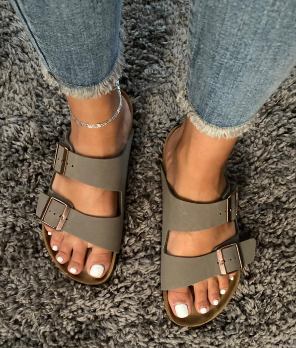 A reviewer wearing the dark gray sandals
