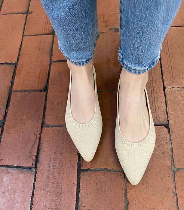 A pair of cream-colored pointed-toe flats