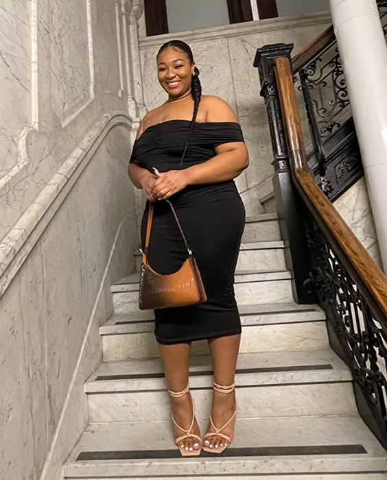 A reviewer in a black dress posing on steps