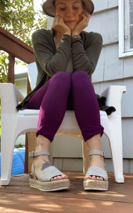 A reviewer is lounging on a deck, wearing white platform sandals.