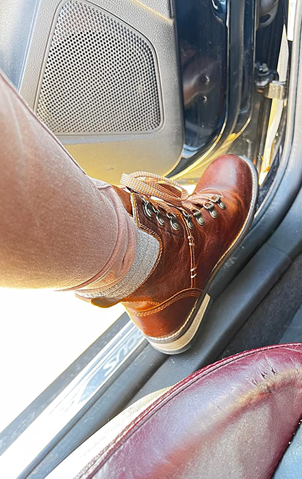 The reviewer is seen sporting a pair of brown leather boots.