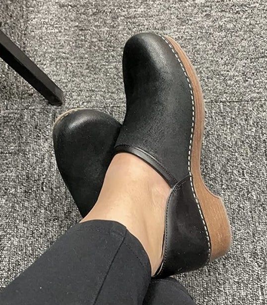 Someone wearing a pair of black clogs
