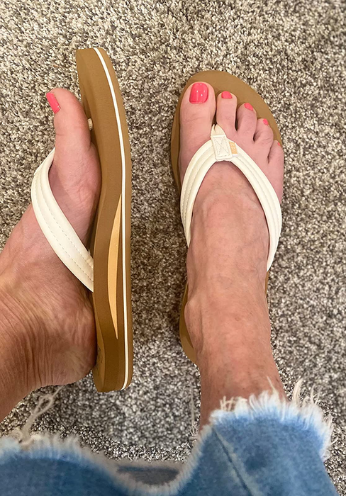 A reviewer wearing the white flip-flops, showcasing a side view