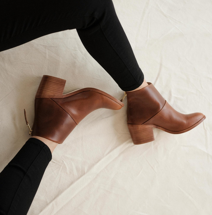 a model wearing the same heeled booties in brown