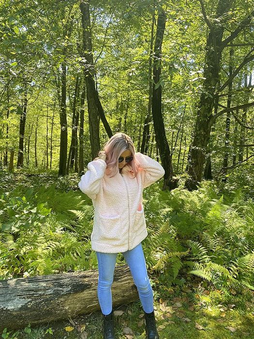 A reviewer styled in a pink coat paired with jeans and boots