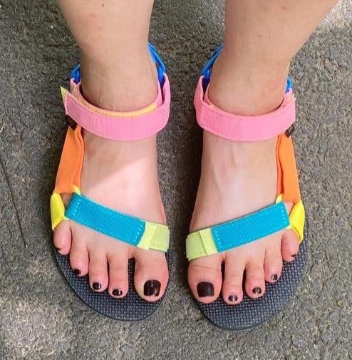 A reviewer showcasing the multicolored sandals
