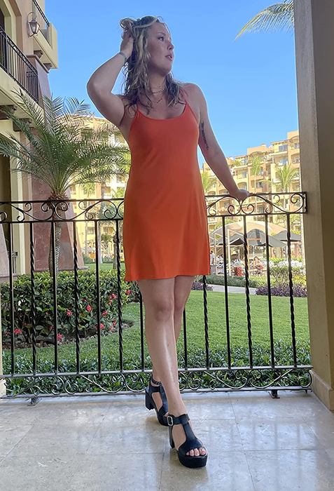 A reviewer is seen wearing black heels with a sundress.