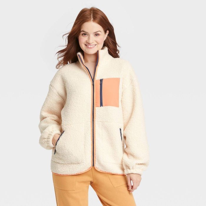 model wearing cream colored zippered sherpa jacket with peach front pocket