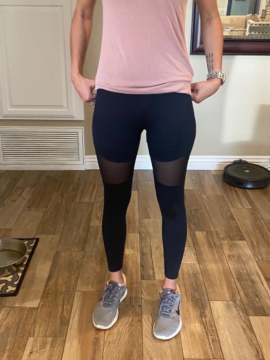 A reviewer showcasing black leggings with stylish mesh panels on the thighs