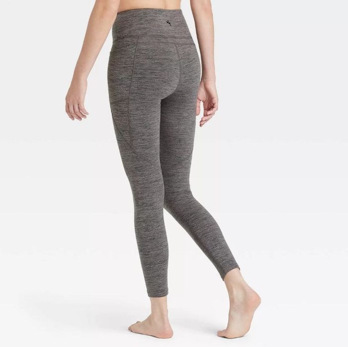 A model wearing the identical high-rise space-dye leggings with a phone pocket, this time in a sleek charcoal grey shade
