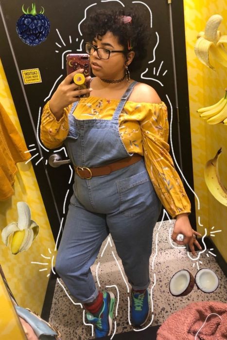 A reviewer showcasing denim overalls
