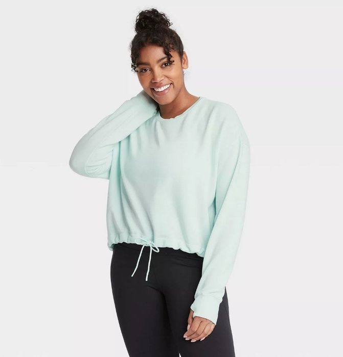 A model wearing a soft fleece crewneck pullover sweatshirt in a refreshing aqua shade