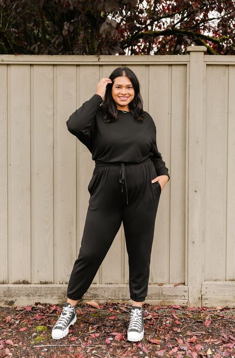 model wearing a long-sleeve black jumpsuit with an elastic waist