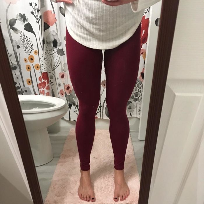 A reviewer showcasing a burgundy pair of leggings