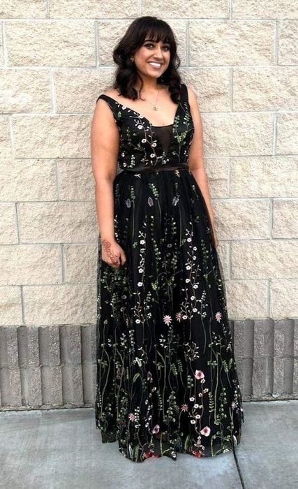 A reviewer sporting a black tulle dress adorned with a delicate floral pattern