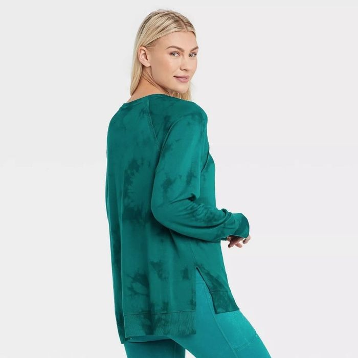A model sporting the same lightweight workout sweatshirt in a vibrant teal tie-dye design