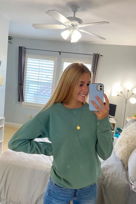 a reviewer wearing the green crewneck sweatshirt