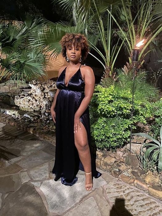 A reviewer donned in a black floor-length dress featuring a daring slit