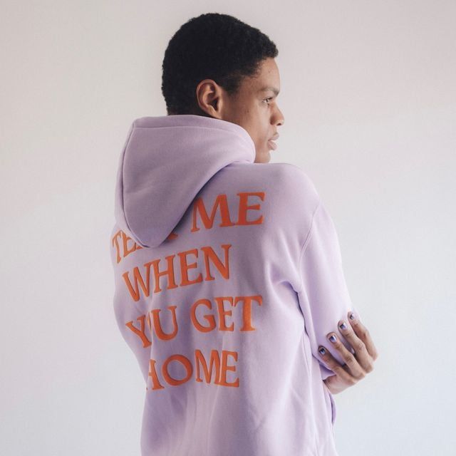 a model wearing the purple hoodie with orange text
