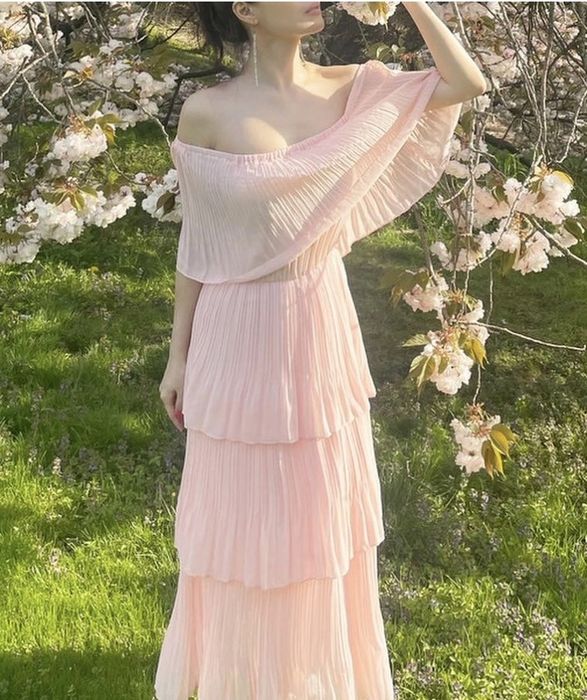 A reviewer donning an off-the-shoulder pink ruffle dress