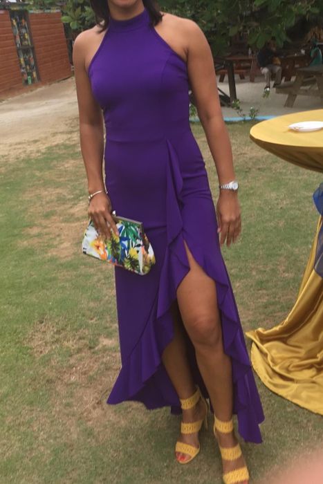A reviewer is seen wearing a striking purple halter dress with a ruffled hem, making a stylish statement.