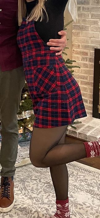 A reviewer modeling a red plaid overall dress