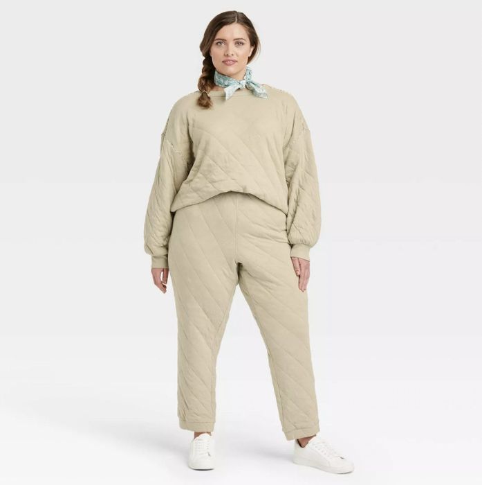 A model wearing the beige quilted sweatshirt with matching pants