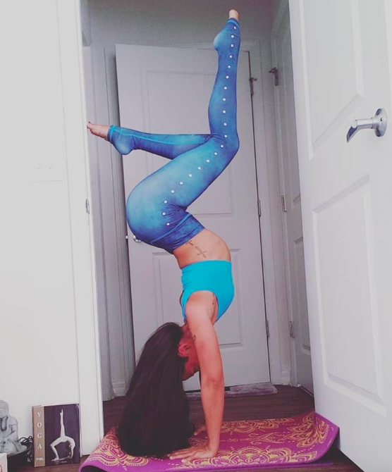 A reviewer wearing the same leggings in a blue shade while performing a yoga headstand