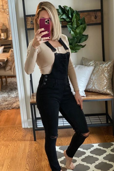 A reviewer showcasing black overalls