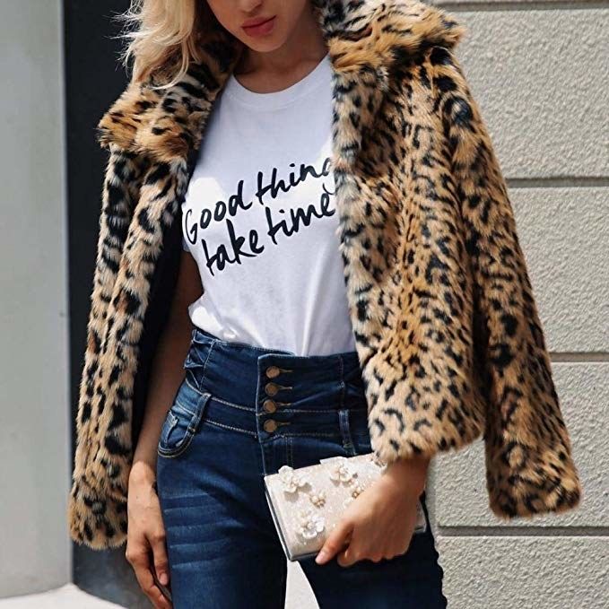 A model in jeans and a T-shirt, casually draping the cheetah print faux-fur jacket over their shoulders