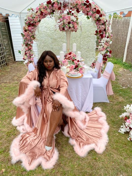 customer image of a reviewer seated at a banquet wearing a custom pink Yinyyinhs feather robe