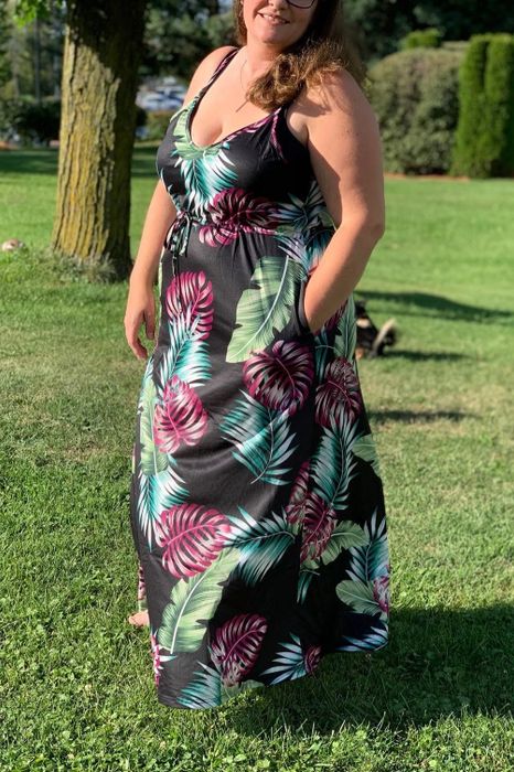 a reviewer wearing the sleeveless dress featuring a vibrant black, green, blue, and magenta palm print