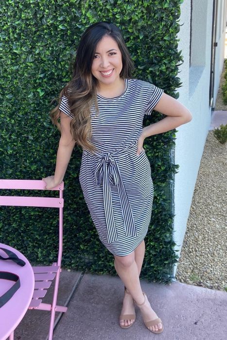 a reviewer wearing the black and white striped dress with the belt securely tied