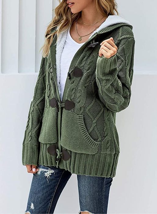 A model is seen wearing a green knit cardigan paired with blue jeans.