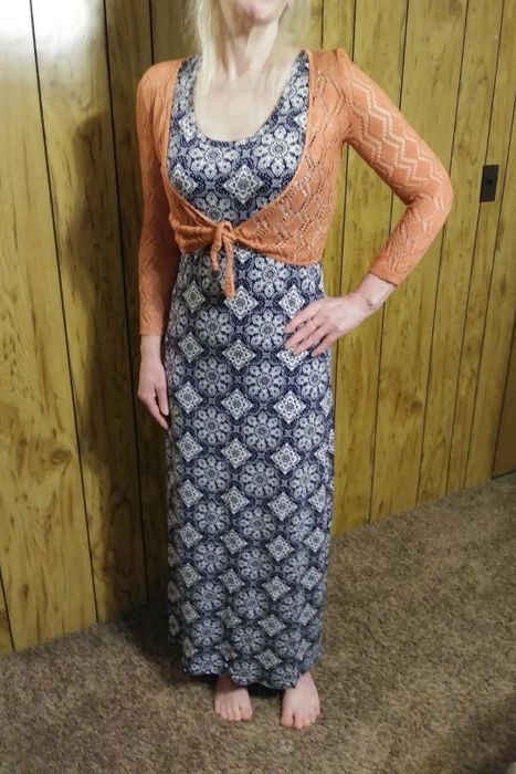 a reviewer wearing the tank dress with a navy and white print, layered under an orange cardigan tied at the front