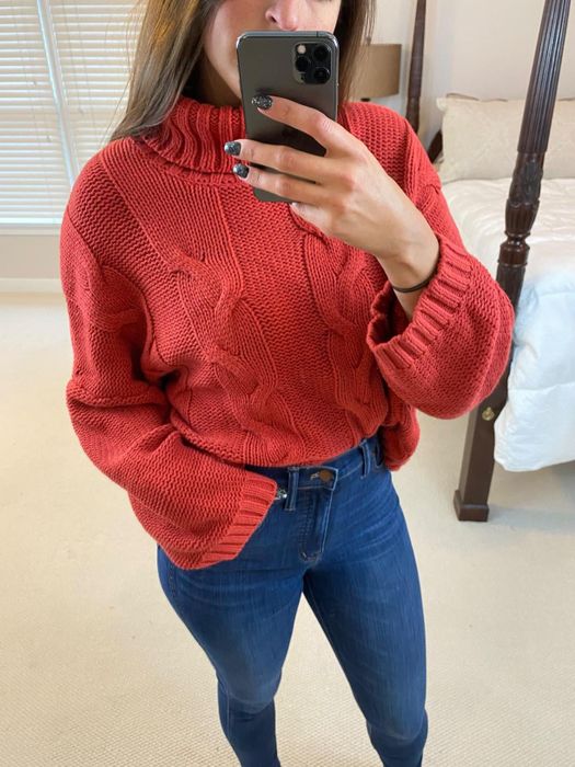 A reviewer shares a photo of themselves in a red turtleneck sweater paired with blue jeans.