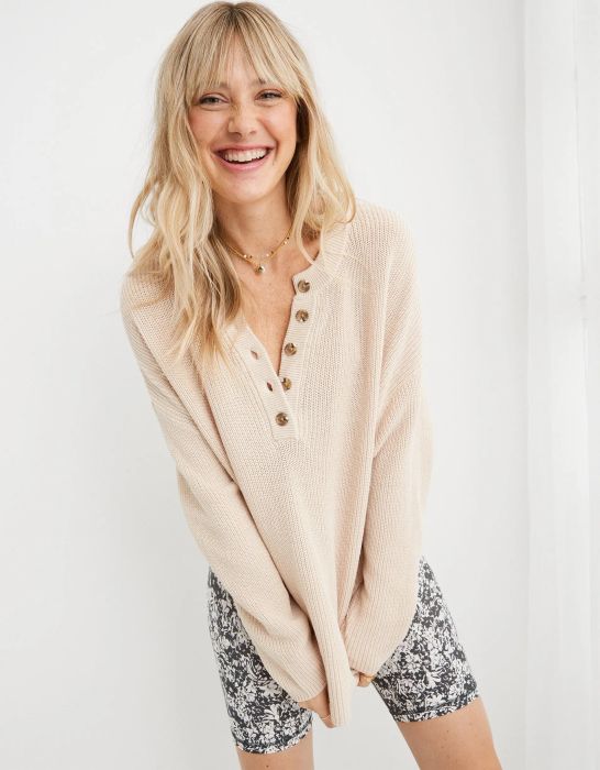 model wearing a beige henley long sleeve sweater with tortoise shell buttons