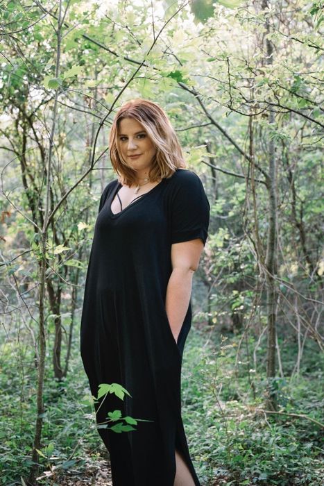 reviewer models a short-sleeve black maxi dress, casually placing hands in the pockets