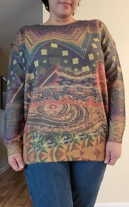 a reviewer modeling the sweater with an abstract design