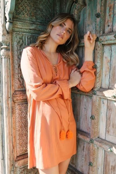 a model wearing a long-sleeve dress featuring a neck tassel tie detail