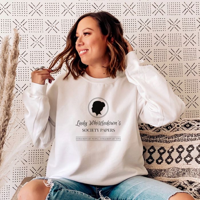 a model poses playfully while wearing the Lady Whistledown's Society Papers sweatshirt in white