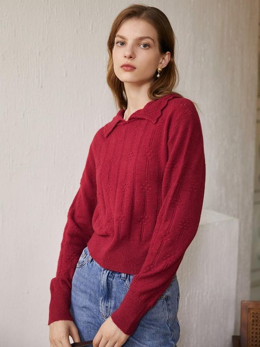 A model wears a red knit polo sweater with blue jeans.