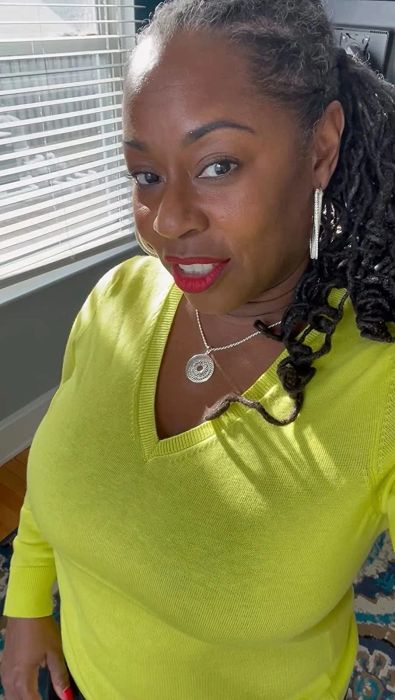 A reviewer wearing the sweater in a vibrant lime green