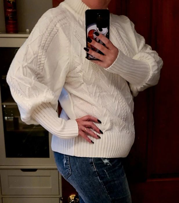 a reviewer showcasing the sweater in a clean white color